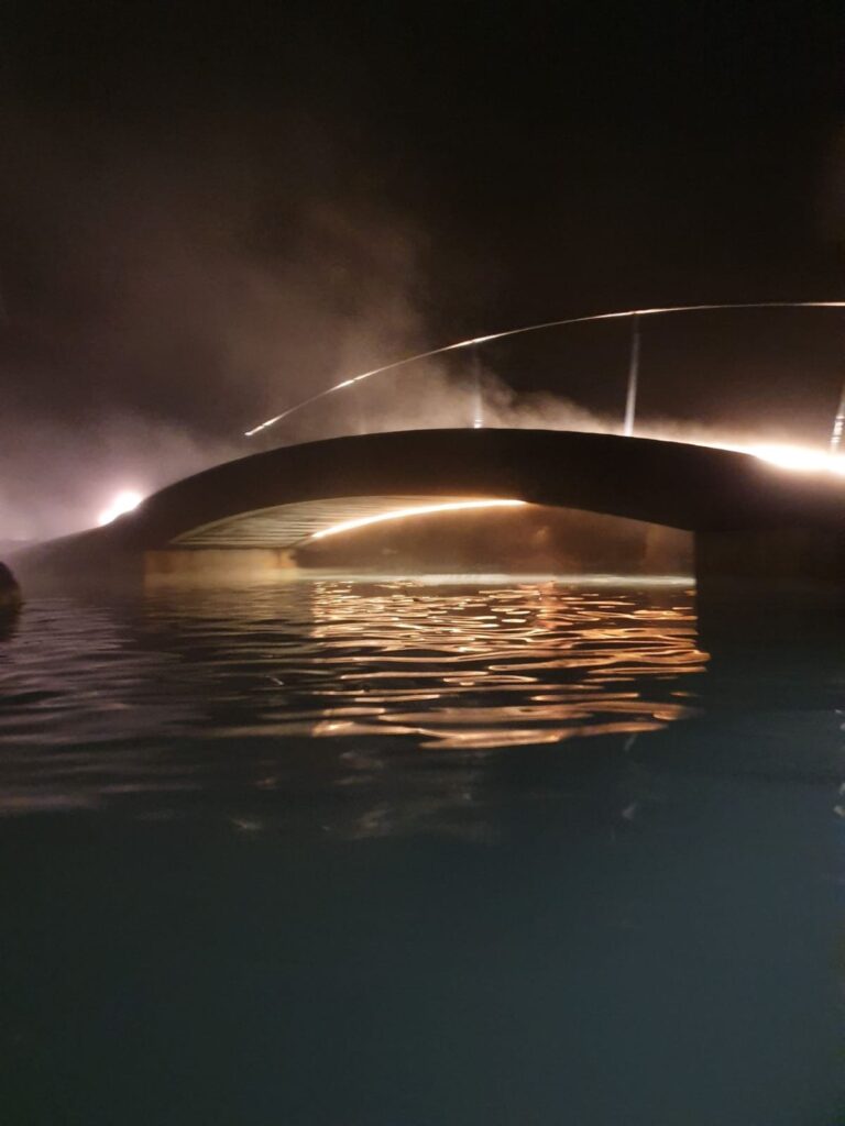 night time picture of the blue lagoon foot bridge taken from in the water